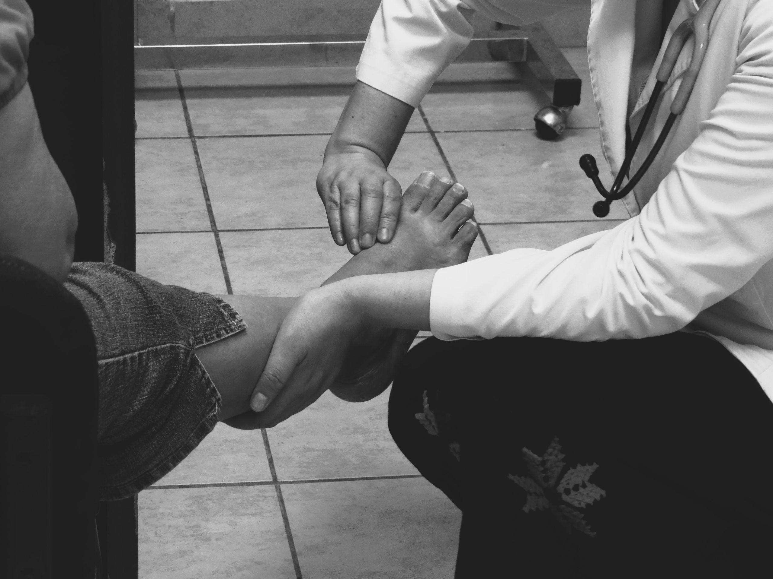 Doctor examines a patient's foot during a medical consultation in a clinic setting.
